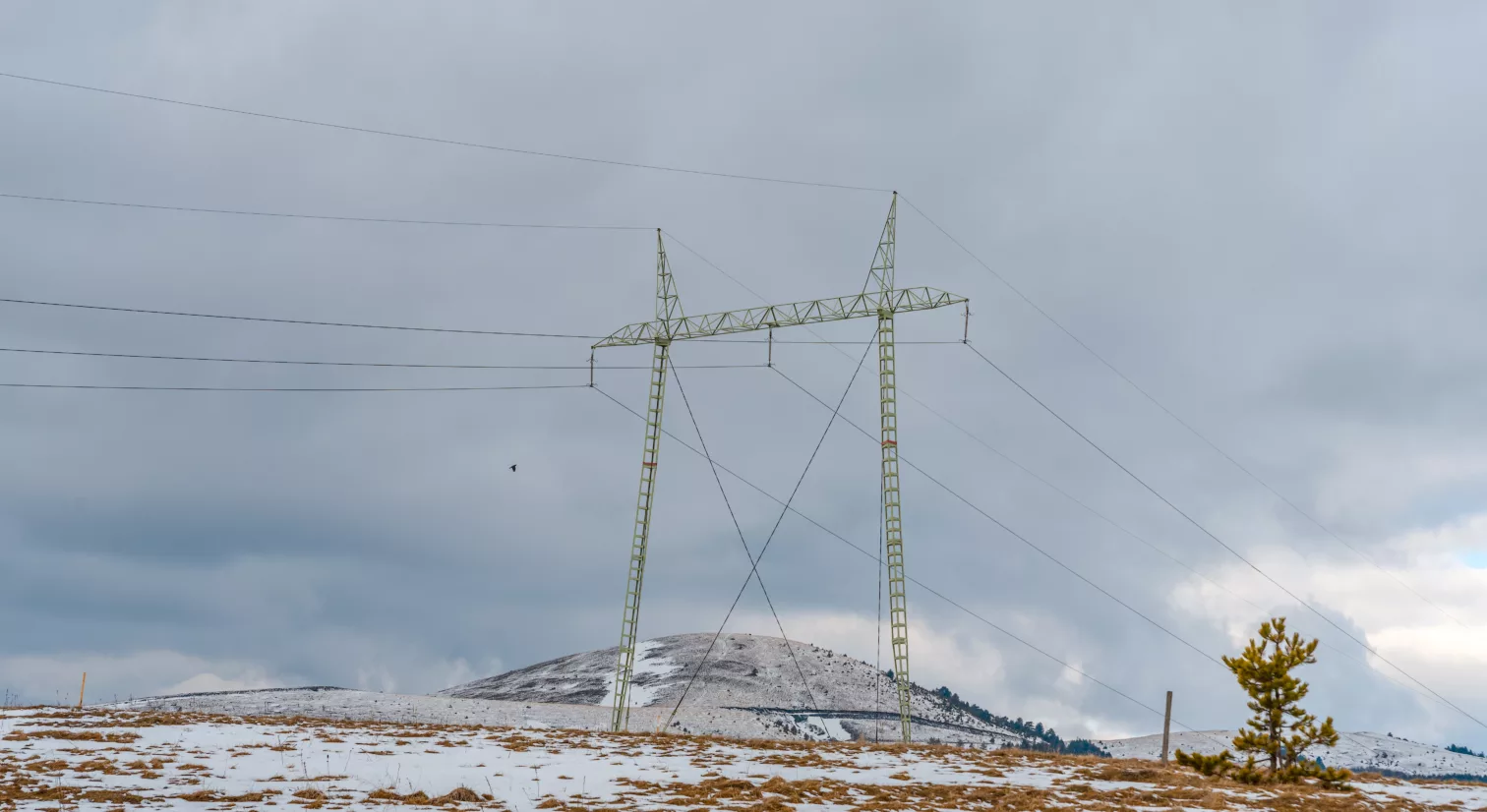En telekommunikasjons-mast på et snødekket jorde med snø, med en grå og overskyet himmel i bakgrunnen.
