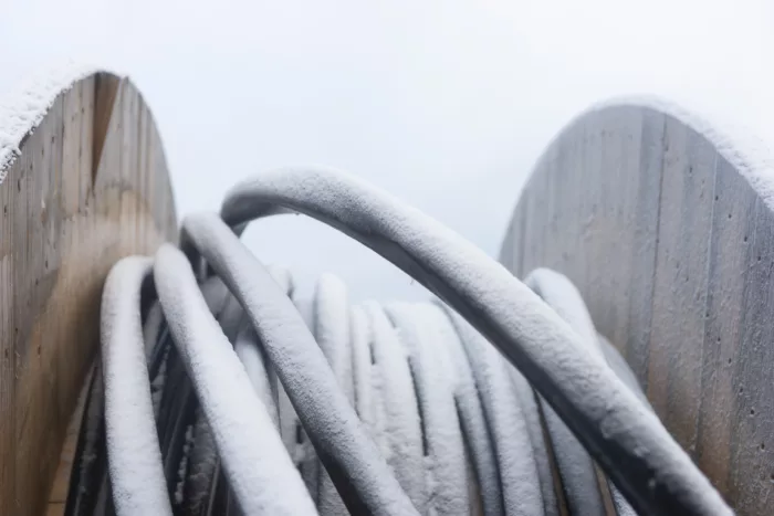 Nærbilde av en kveil med fiber-kabler med frost og snø på toppen.
